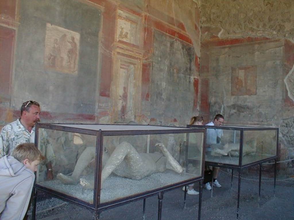 VII.9.7 and VII.9.8 Pompeii. May 2004. Victim number 11 (front) in display case in Macellum.