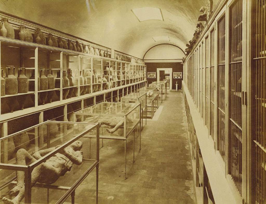 Victim number 9, on left at front, interior of Pompeii Museum before 1889, (Room II). Photo: Edizioni Brogi.
Photo courtesy of Eugene Dwyer.
According to Dwyer, (p.99), starting from the left case, 
Man, victim 9, See Brogi 5573.
Man, victim 6, See Brogi 5574.
Man, victim 1, See Brogi 5575.
Woman, victim 10, See Brogi 5576.
Woman, victim 4, See Brogi 5577.
Two women, victims 2 & 3; See Brogi 5578.

Room III, Sick Man, victim 7; See Brogi 5579.
Watchdog, victim 8; See Brogi 5580; (the watchdog was later removed to Room II). 

See Dwyer, E., 2010. Pompeii’s Living Statues. Ann Arbor: Univ of Michigan Press, (p.94).

In his description of this plaster-cast in his Guida di Pompei, 1877, Fiorelli described –
“Another man [victim 9], on his back, with his legs and arms drawn up, protected by a cloak and sandals. (Reg. VI, Ins. XIV, via nona).”
See Fiorelli, Guida di Pompei, [Rome, 1877,] p.88-89. 
(Note: Fiorelli wrote that victim 9 was found in Reg. VI. XIV, via nona, and that victim 10 was found at Reg. VI. XIV, cardo, and yet they had been found together).

