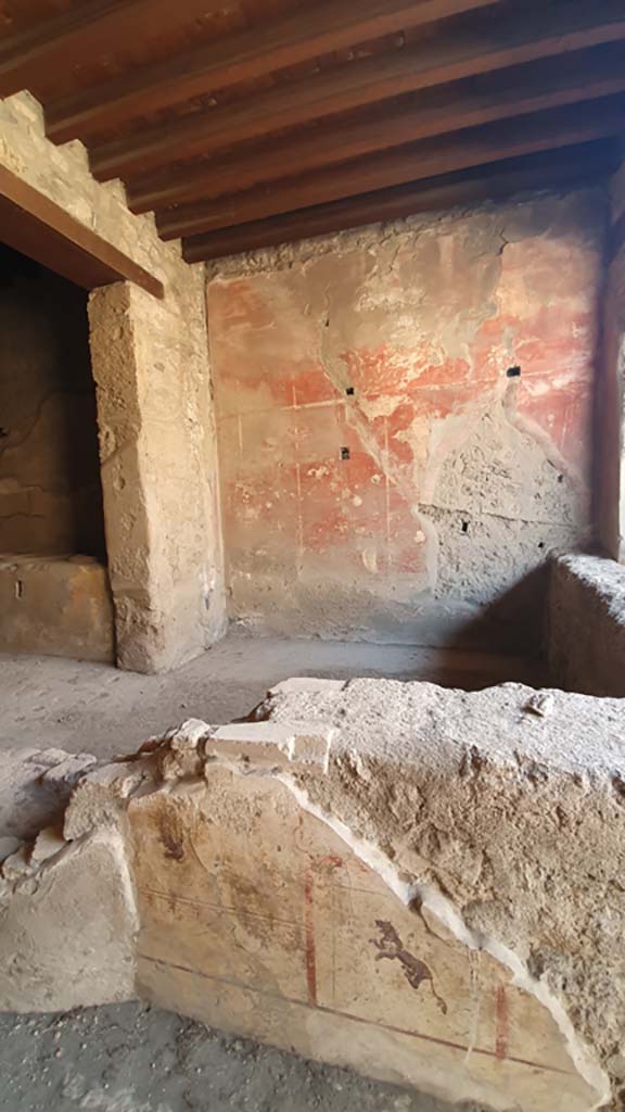 II.9.4, Pompeii. May 2018.  Remains of painted plaster on east side end of counter.
Photo courtesy of Buzz Ferebee. 
