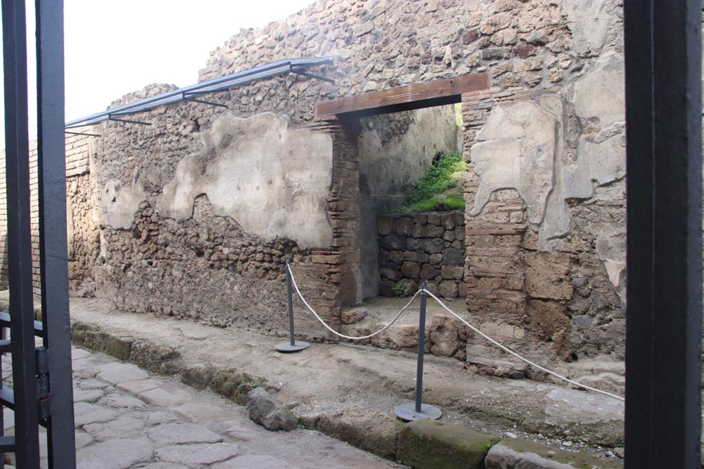 V.7.6 Pompeii. October 2023. Looking east towards entrance doorway and remaining plaster with graffiti. Photo courtesy of Klaus Heese. 