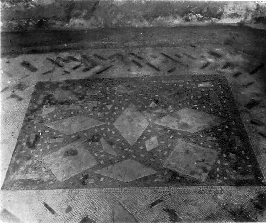 VII.7.5 Pompeii. c.1930. Flooring of central vaulted room on east side of atrium.
According to Blake –
The vaulted room to the right of the atrium of this house, through its various transformations, gives some slight help in dating this type of floor. 
The original pavement was apparently a lithostroton of the Palestrina type, if one may judge by the strip composed of oblong tesserae which still remains near the back wall. Later a wall of badly wearing yellow tufa, a variety not used until the middle of the first century AD, was constructed upon the floor. The pavement is clearly earlier than the cement floor of the atrium and may well belong to the same period as those of the alae. The use of coloured marbles rather than limestones suggests the age of Augustus, or a time slightly previous. In this particular floor, there is a definite attempt to make a design even out of irregular pieces. The centre has lozenges of giallo or bigio laid in a rough pattern in the background of fine black tesserae (0.6cm to 0.07cm), while the background itself has been spotted with oblong tesserae of white. Around this runs a broad white border in which are sprinkled long narrow pieces of giallo, affricano, and rosso. 
See Blake, M., (1930). The pavements of the Roman Buildings of the Republic and Early Empire. Rome, MAAR, 8, (p.61 & Pl.13, tav. 2)


