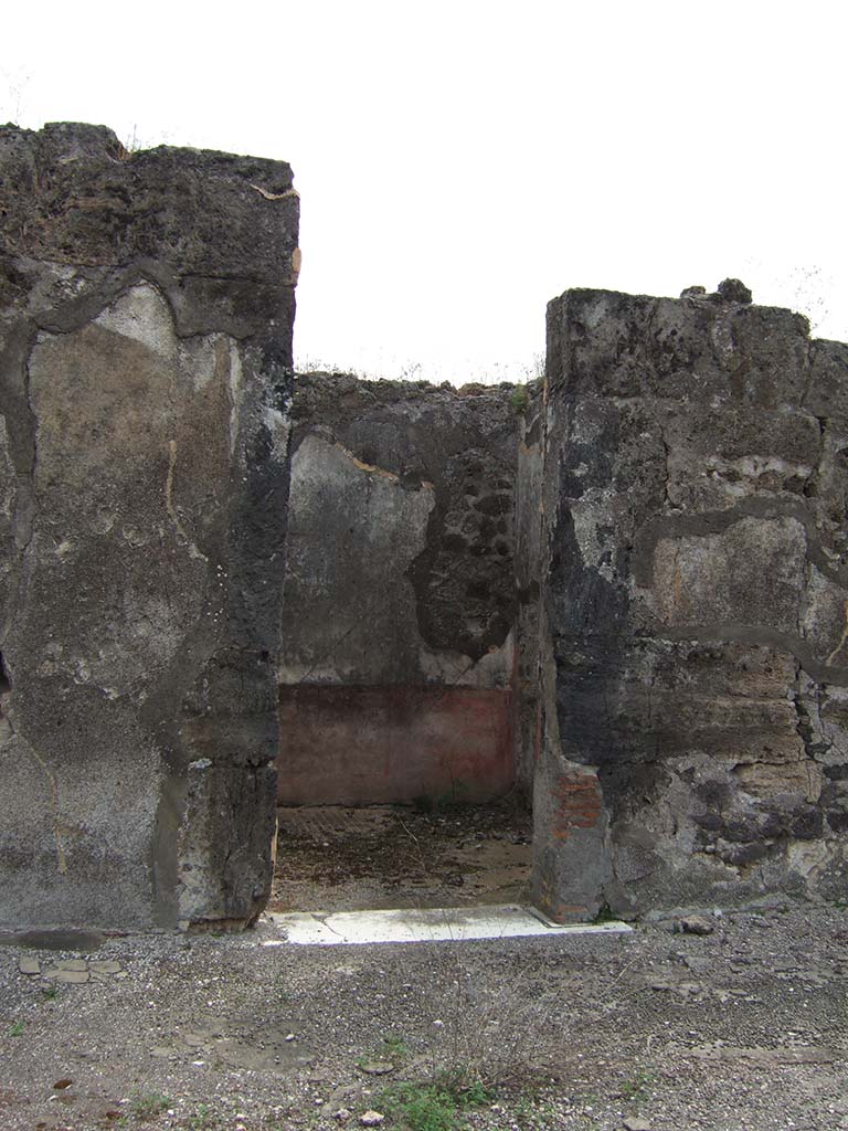 VIII.2.34 Pompeii. May 2006. Doorway to cubiculum ‘f’, in centre of east side of atrium.
The floor in this room was identical to room ‘e’, being of cocciopesto with dots of small white tesserae in regular lines.
The east wall can be seen through the doorway, with red zoccolo which had painted plants in panels separated from a central panel.
The middle zone of the wall would have been white.
