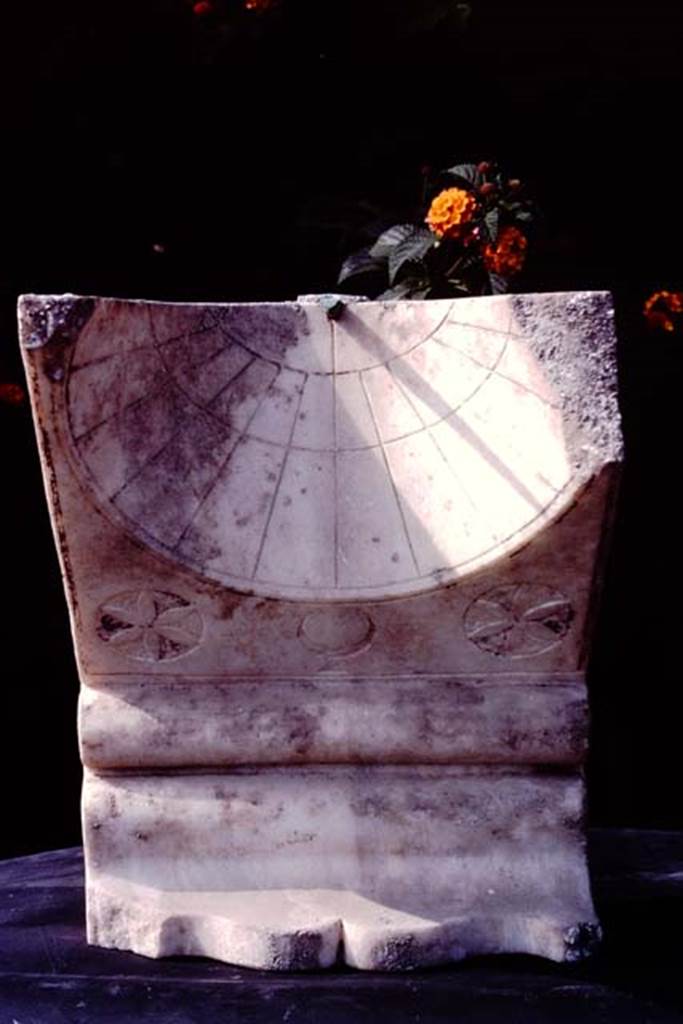 Oplontis, c.1974-77. Room 32. Sundial.
Source: The Wilhelmina and Stanley A. Jashemski archive in the University of Maryland Library, Special Collections (See collection page) and made available under the Creative Commons Attribution-Non Commercial License v.4. See Licence and use details. Oplo0008
According to Wilhelmina – 
“Against the east side of the fountain we found the cavity left by a large tree. The two carbonized chestnuts found in the lapilli in the south-east corner of the garden, at the height of the ceiling beams, probably fell from a branch of this tree. The sundial in the north-east corner had no doubt become useless as the large tree shaded the garden”.
See Jashemski, W. F., 1993. The Gardens of Pompeii, Volume II: Appendices. New York: Caratzas. (p.294)
