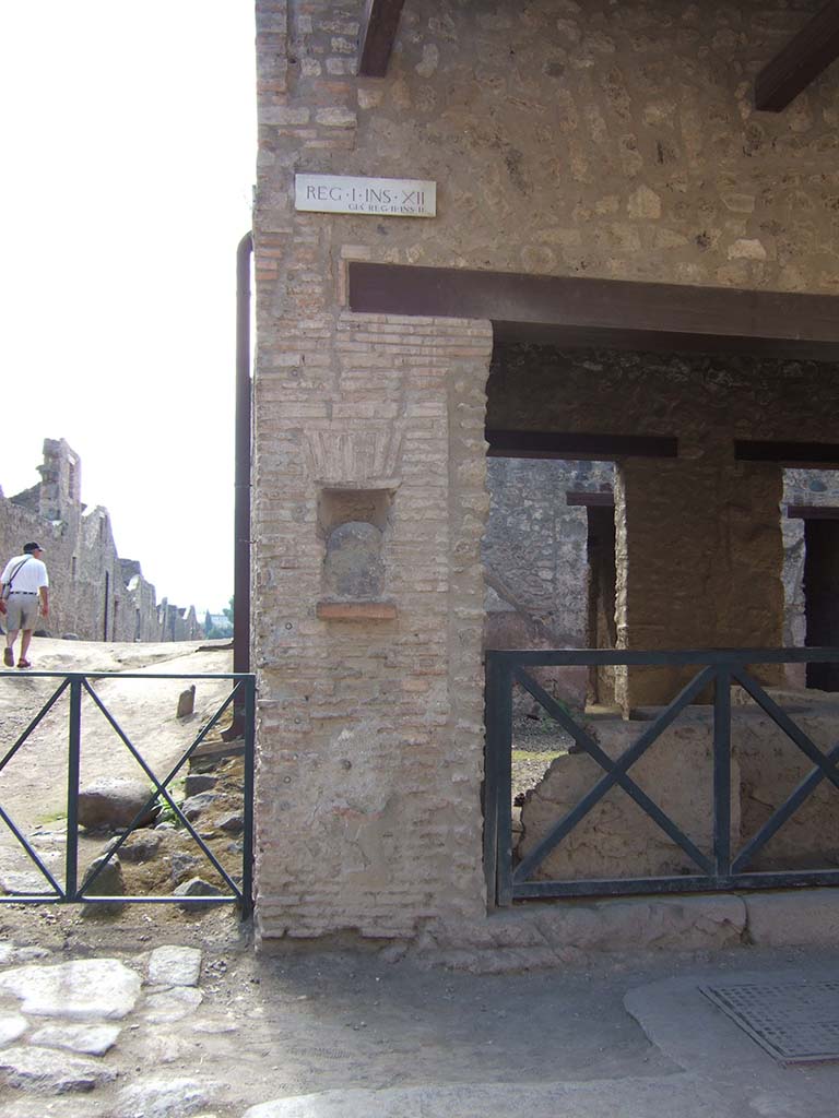 Street shrine or niche outside I.12.5 Pompeii. September 2005.
This is on Via dell Abbondanza, at the corner with Vicolo dei Fuggiaschi. 
According to Della Corte, on the red pilaster which ended the insula on the east side, two electoral programmes were found.
The first -
GAVIVM II VIR.      [CIL IV 7442]

The second -
AMPLIATVM L F AED
        VICINI
        SVRGITE ET
        ROGATE
        LVTATI F[ac]       [CIL IV 7443]

The first line of the second inscription had larger letters than the subsequent lines.
The text was placed towards the right, because the pilaster was interrupted in the middle by a rectangular niche.
In the niche was fixed a coarse rough stone resembling the outline of a human head, not the usual marble bust, as often seen here and there in the street.
See Notizie degli Scavi, 1914, (p.204).

According to Epigraphik-Datenbank Clauss/Slaby (See www.manfredclauss.de), these read

Gavium
IIvir(um)      [CIL IV 7442]

Ampliatum L(uci) f(ilium) aed(ilem)
Vicini
surgite et
rogate
lutati f[ac(iatis)]      [CIL IV 7443]

