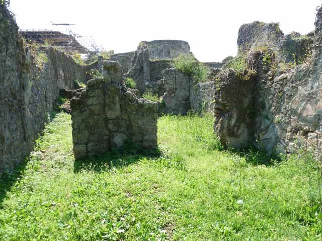 VI.16.11 Pompeii. May 2010. Looking west across shop to corridor to rear, on left, and rear room in north-west corner, on right. Originally, on the west wall between the corridor and the rear room was a lararium. According to Boyce, there was a ruined niche in the west wall, coated with white stucco bordered with red stripes. Red and green garlands were painted on the back wall of it. See Notizie degli Scavi di Antichità, 1908, p. 58. See Boyce G. K., 1937. Corpus of the Lararia of Pompeii. Rome: MAAR 14.  (p. 58, no.222).
