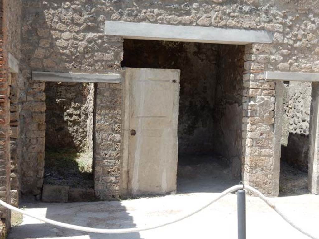 I.7.19 Pompeii. May 2017. Doorways to rooms in north-west corner of atrium. Photo courtesy of Buzz Ferebee.
According to NdS –
“Cubiculum which, due to its unusual shape, seems to have been adapted in the more recent times into an exedra, (measuring 2.40 x 1.80m), originally open onto the atrium. It was possible to draw the complete imprint of the door that with a single leaf served to close the cubiculum, and inside the wooden framework of the bed that occupied almost the entire width of the small room. At the ends of the bed and especially at the lower headboard, the pieces of bone that inlaid the wooden panels with geometric design remained in the compactness of the ash layer. The ceiling was flat, and above it there were traces of the upper room.  
Near the entrance of this cubiculum, it was possible to make the plaster of the body of an 8 to 10 year old boy who, from his special position (the head sunk into the lapilli and the lower half of the body into the ashes), was thought to have fallen headlong from the upper floor of the house, with a wicker basket that he carried tightly with one of his arms and which was found next to him (fig.2, p. 360).
The unfortunate boy fell, with one of his hands brought variously to his mouth to protect himself from the asphyxiating fumes, and with the other hand raised aloft as if to try to save the basket in the fall, with which, he had deluded himself into thinking he was carrying a few provisions for his desperate escape.”

(Cubicolo che per la sua forma inusitata sembra essere stato adattato negli ultimi tempi nel vano di un exedra originariamente aperta sull’atrio (m. 2.40 x 1.80). si pote trarre l’impronta completa della porta che con un sol battente serviva a chiudere il cubicolo, e all’interno l’impronta della impalcatura in legno del letto che occupava quasi tutta l’ampiezza del piccolo ambiente. Alle due testate del letto e soprattutto alla testata inferiore sono rimaste nella compattezza dello strato di cenere le filettature in osso che intarsiavano di disegno geometrico i pannelli in legno. Il soffitto e piano e al disopra di esso restano le tracce dell’ambiente superiore.
Presso l’ingresso di questo cubicolo si pote eseguire la forma in gesso del corpo di un fanciulletto di otto o dieci anni che dalla sua speciale positura (il capo affondato nel lapillo e la meta inferiore del corpo nella cenere) si dove pensare fosse precipitato a capo fitto dal piano superiore della casa con un cestella di vimini che recava stretto con l’uno dei bracci e che gli fu trovato accanto (fig.2, p. 360).
Precipito il disgraziato fanciullo con l’una delle mani portata variamente alla bocca per ripararsi dalle esallanoni asfissianti e con l’altra mano sollevata in alto come per tentar di salvare nella caduta il cestello con cui si era illuso di portar con se poche cibarie per la disperata sua fuga.)

See Notizie degli Scavi, 1929, (p.359-60).


