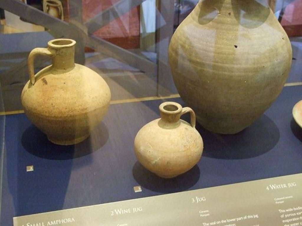 I.10.4 Pompeii.  Small ceramic jug (at centre front). SAP 4981. The seal on the lower part of this jug bears the inscription, CN. ATEIUS ARRETINUS, LIBERTUS A ATEIO. It refers to Arretinus, a freedman (former slave) whose pottery business was operated in the town of Ateio around 30-40 BC. Photographed at “A Day in Pompeii” exhibition at Melbourne Museum.  September 2009.