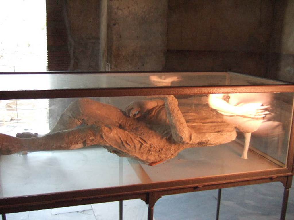 Plaster cast of a supine man with arms and legs slightly contracted, wrapped in a cloak.
Found 23rd April 1875 in NE corner of VI.14 in middle of Via Stabiana, four metres above ground level in the ash layer.
He was found next to the woman with her tunic raised over her head.
When photographed, this was on display in VII.1.8, the Stabian Baths, mens changing room. 
See SSANP: Boscoreale Antiquarium exhibition catalogue: The Casts, 5 March  20 December 2010. (p.6 and 7)
See Garcia y Garcia, L., 2006. Danni di guerra a Pompei. Rome: LErma di Bretschneider. (p.193, Figs 448-9).
  September 2005.