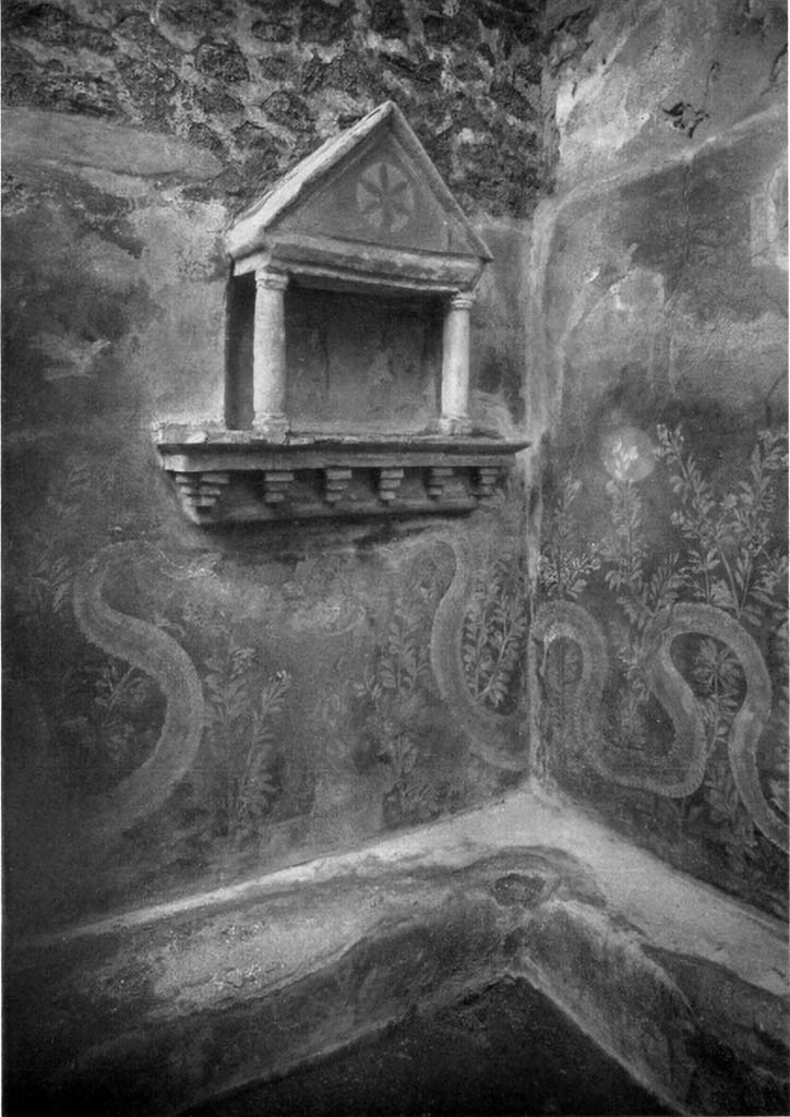 VI.15.23 Pompeii. 1930s? Kitchen in south-west corner of peristyle.
Lararium in north-west corner of kitchen, near doorway to south portico.
Boyce said, against the wall below the aedicula and that of the entrance doorway was a masonry seat (h.0.30).
It was decorated upon a background of red with painted luxuriant foliage which covered the front surface of the bench.
It extended above the bench to form a background for the serpents.
See Boyce G. K., 1937. Corpus of the Lararia of Pompeii. Rome: MAAR 14.  (p.56, no.219, and Pl.15, 1 and 2)
