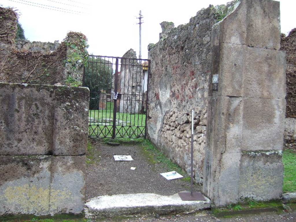 VII.4.59 Pompeii. December 2005. Entrance c and fauces d to the House of the Black Wall.The house was named after the exedra or triclinium y discovered with painted IV style black walls. Due to the bombing in the night of 13th September 1943, much damage was done. The IV style stucco and plaster in the cubicula near the atrium was lost. In the peristyle, the plaster on the columns and the paintings on the walls were damaged, and the east wall was partly demolished. Worst of all was the damage to part of the famous IV style triclinium.  When excavated the triclinium had been found missing most of the decoration on its east side. After the bombing, most of the west side was lost as well. The south wall was partially destroyed. Many interesting small paintings were destroyed.
The walls of this triclinium were restored in the following years from many fragments. Partial restoration was also completed in the atrium and peristyle.
See Garcia y Garcia, L., 2006. Danni di guerra a Pompei. Rome: L’Erma di Bretschneider. (p.101)
