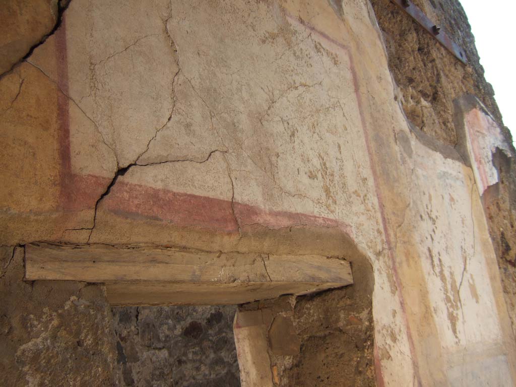 VII.7.13 Pompeii. September 2005. Remains of painted wall decoration above doorway, on east wall of peristyle.