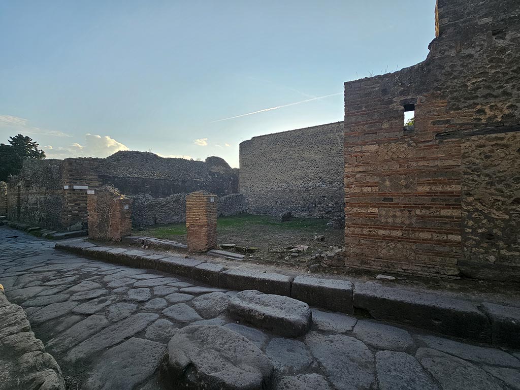 VII.11.17 and 16 Pompeii. November 2024. 
Looking south-west from Vicolo del Lupanare towards two shops at junction with Vicolo degli Scheletri, on left.
Photo courtesy of Annette Haug.

