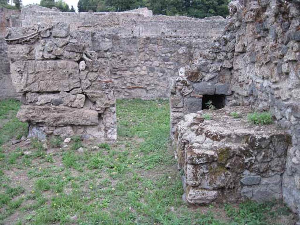 VIII.7.6 Pompeii. September 2010. Photo courtesy of Drew Baker.
Looking east from atrium of VIII.7.6, doorway in south-east corner leading to room in VIII.7.5.  According to Fiorelli, in the atrium area was found a hearth and oven in proximity of the workshop, to service its feeding needs.
See Pappalardo, U., 2001. La Descrizione di Pompei per Giuseppe Fiorelli (1875). Napoli: Massa Editore. (p.131)
