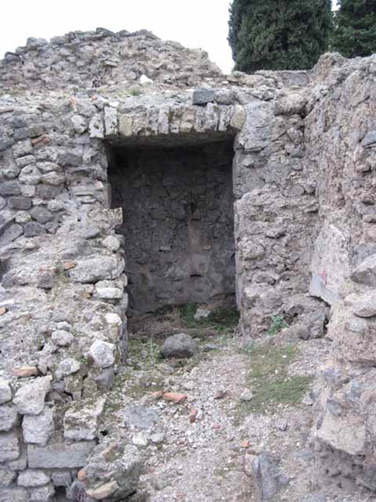 VIII.7.22/23/24 Pompeii. October 2010. Looking west to doorway to corridor to lower rooms from VIII.7.22/23, access is to the right through the doorway. Photo and information courtesy of Drew Baker/Gareth Beale/Hembo Pagi.

Somewhere in this corridor area, Boyce described a lararium.
According to Boyce, in the north wall of a corridor leading from the underground kitchen to the posticum at VIII.7.22, was a large arched niche.
This was I.0 metre high, 0.85 wide, 0.50 deep and 0.70 above the floor.
The back wall of the niche was painted red, and on it was the figure of Fortuna, clad in a green tunic and yellow mantle.
In her left hand she held a cornucopia, and in her right, a rudder.
To the left of her feet was a large globe.
The side walls of the niche and the area under the feet of the goddess were decorated with green plants.
See Boyce G. K., 1937. Corpus of the Lararia of Pompeii. Rome: MAAR 14.  (p.78, no:378)

Fiorelli describes, VIII.7.22 as a corridor belonging to VIII.7.24, with stairs to upper floor. 
Nearby is the kitchen, in which remains the niche of the Penates, with the image of Fortuna with cornucopia and rudder.
See Pappalardo, U., 2001. La Descrizione di Pompei per Giuseppe Fiorelli (1875). Napoli: Massa Editore. (p.134)
