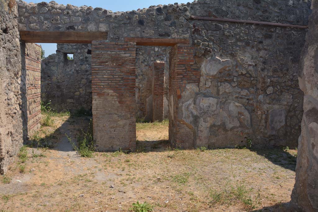 IX.7.19 Pompeii. July 2017. 
Looking south across atrium towards two doorways, the one on the right leading into room e, at the rear of room d, which is the shop at IX.7.18.
Foto Annette Haug, ERC Grant 681269 DÉCOR.

The other doorway on the left, the rear right of the atrium, leading to room f, a corridor leading to the rear of the house including kitchen and garden.
According to Mau, a pile of material at the entrance of the corridor f, could have been the first step of a stairway to the upper rooms. 

Room i was the kitchen with the latrine. 
The entrance doorway was very narrow and cut obliquely across the wall in the corner. 
Near the south wall was the hearth, and the latrine. 
Near the north wall was a large pilaster (1.15 x 1.07) composed of opera incerta (lava) and limestone cut into the form of bricks. 
This pilaster was joined with the east wall for an arch, on which was a narrow platform between the pilaster and the east and north walls. 

According to Boyce, a small room, room k, located between kitchen and garden on the south side of the house, was originally part of the garden.
This small room had a doorway into the kitchen. 
Then the room was separated from the garden and the doorway to the kitchen was bricked-up.
On the east wall of this new room was a lararium, with a Genius standing to the right of a tripod.
On the other side of the tripod stood the tibicen. Below and to the right, ran a camillus. 
Below this were two serpents, gliding, one from each side, amongst plants towards an altar.
Between this painting and the south-east corner of the room were painted, two pots, a large bottle, sausages, a calf’s head, ribs of pork on a spit, and a phallus.
See Boyce G. K., 1937. Corpus of the Lararia of Pompeii. Rome: MAAR 14. (p.88, no.438) 
See Giacobello, F., 2008. Larari Pompeiani: Iconografia e culto dei Lari in ambito domestico. Milano: LED Edizioni, (p.209, no.106)

The following items were found on 28th December 1880, in “ultima camera interna a destra dell’atriolo” – the last internal room on the right from the atrium. (This would be the room k with the lararium painting).  
The remains of a small wooden box with bronze lock and decorations, was found together with the following items gathered together –
A bronze lamp (a lantern to a lamp with two handles made to look like branches surmounted by a shield – Naples    Archaeological Museum, inventory number: 118253
A terracotta cup with two handles - Naples Archaeological Museum, inventory number: 113025
A terracotta lamp with separate handle - Naples Archaeological Museum, inventory numbers: 117227, 117228
A glass bottle - Naples Archaeological Museum, inventory number: 114908
Also found were various bronze, terracotta, bone, iron and marble items, as well as 42 containers with various colours.
See Mau in Bullettino dell’Instituto di Corrispondenza Archeologica (DAIR), 1883, (p. 82-3).
See Sogliano in Notizie degli Scavi di Antichità, 1880, (p. 491 and p. 493-4).
Thanks to Raffaele Prisciandaro for his assistance in locating the inventory numbers of the items in the Naples Archaeological Museum.

According to Notizie degli Scavi di Antichità, 1881, p.63, the following objects were found in the presence of scholars of the r. Istituto di belle arti di Napoli on 17th February 1881. 
They were found in one of the internal rooms.
Bronze basin with damage in the middle, and two unsoldered handles that finished with the head of a sea-horse - Naples Archaeological Museum, inventory number 118197
Bronze tweezers or small pliers.
Two bronze hinges.      
A small bronze coin.
