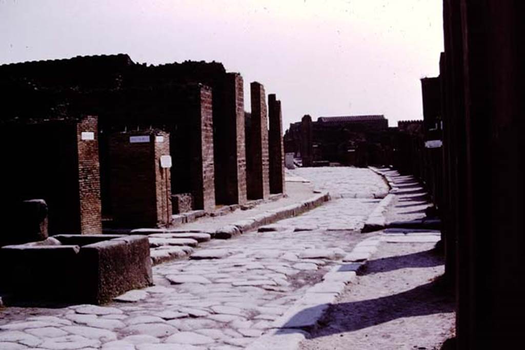 Via dell’Abbondanza, Pompeii. 1975. Looking east from near fountain at VII.14.13/14.
Photo by Stanley A. Jashemski.   
Source: The Wilhelmina and Stanley A. Jashemski archive in the University of Maryland Library, Special Collections (See collection page) and made available under the Creative Commons Attribution-Non Commercial License v.4. See Licence and use details. J75f0372
