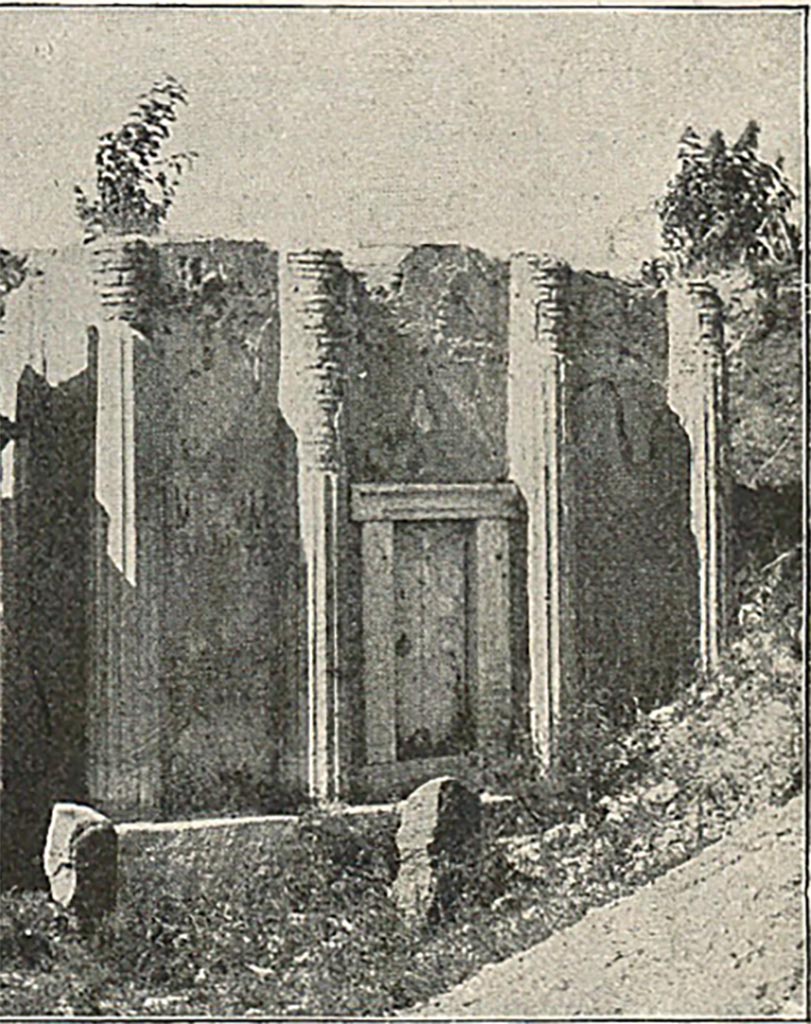FP6 Pompeii. Detail from late 19th century photo.
According to Mau, “the entrance to the tomb was in front, and closed by a block of travertine. 
It led, not to a sepulchral chamber, but to a stairway by which one ascended to the second storey.
Here statues were placed, but the exact form of the upper part cannot be determined. 
The finding of five tufa capitals suggests that the second storey may have been a columnar structure, like that of the tomb of the Istacidii. 
When the excavations are carried further east enough other fragments will perhaps be found to make a complete restoration possible. 
One of the statues is of a man holding a roll of papyrus in his hand, with a round manuscript case, scrinium, at his feet.”
See Mau, A., 1907, translated by Kelsey F. W. Pompeii: Its Life and Art. New York: Macmillan. (p. 435).
