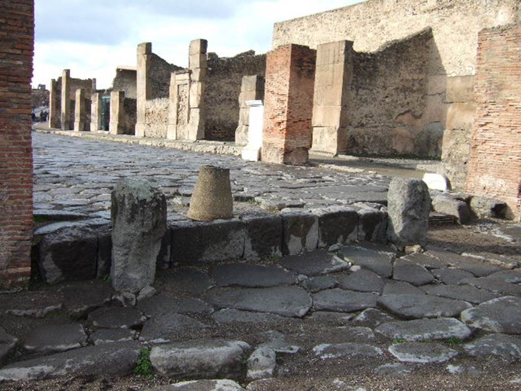 Arch of Marcus Holconius Rufus. December 2005. Remains of pillars of the north side of the arch, on right. Looking west through arch along Via dell Abbondanza.
